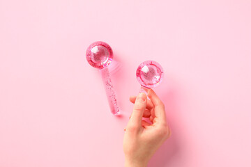 Ice globes for facials, cooling globes on female hand on pink background.
