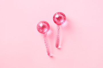 Ice globes for facials, face massager tool on pink background.