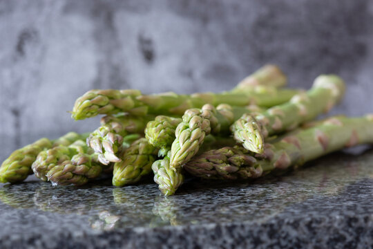 Raw Organic Asparagus, Freshly Picked, On A Black Granite Worktop Surface. Fresh Seasonal Produce Concept