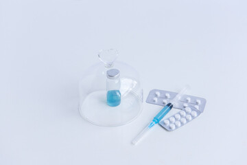 On white isolated background lie a syringe with medicine, a vial with a blue vaccine against...