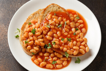 Baked beans on toast in tomato sauce on white plate