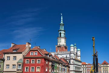 Historic tenement houses, historic town hall tower and construction machine on the market square in Poznan