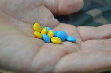 Mano solidaria con caramelos azul y amarillo.