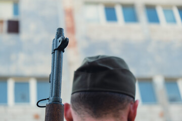 Back view of unrecognizable man in body armor during war weapon. Soldier hold the gun next to...