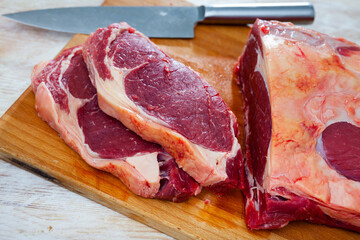 Pieces of raw boneless tenderloin beef on wooden background prepared for roasting