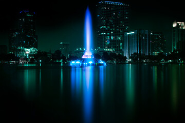 Orlando, Florida fountain at night lighting up Lake Eola with downtown buildings in the background...