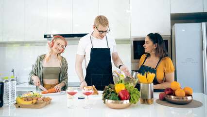 Cheerful family of young mother and father with their teenage daughter enjoying in modern kitchen while preparing healthy breakfast and juice while tasting food