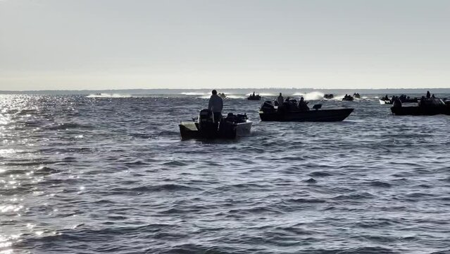 Boats zoom off and splash across the waves to start a fishing tournament 