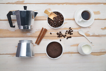 Cup of coffee, geyser coffee maker, milk and beans coffee on ,white wooden table. top view.