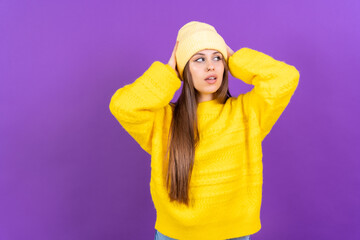 Close up portrait of young caucasian woman in wool sweater isolated on yellow studio background