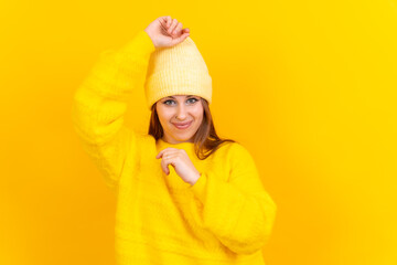 Photo portrait of a young woman dancing very happy isolated on a yellow background, wool sweater