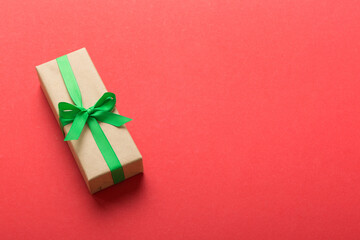 Wrapped christmas or other holiday handmade present in craft paper with colored ribbon. Present box, decoration of gift on table, top view with copy space