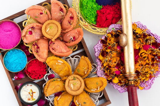 Kesar Gujiya, Pink Rose Gujiya, Chandrakala, Suryakala Decorated In Wooden Tray With Holi Color Powder Gulal, Abeer, Abir, Rang, Water Brass Gun Pichkari And Dried Petals Of Tesu, Kesu Or Palash Phool
