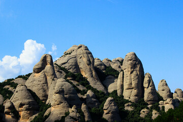 a peak mountain of finger-like rock formations seen against the blue sky with few white clouds in the corner