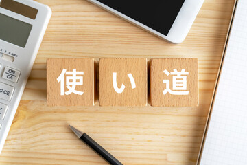 使い道と書かれたブロック、電卓、スマホ、ノート
