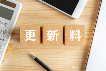 更新料と書かれたブロック、電卓、スマホ、ノート
