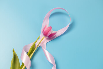 One pink ribbon with a tulip on a blue background.