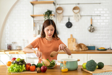 Obraz na płótnie Canvas Portrait of beauty body slim healthy asian woman having fun cooking and preparing cooking vegan food healthy eat with fresh vegetable salad in kitchen at home.Diet concept.Fitness and healthy food