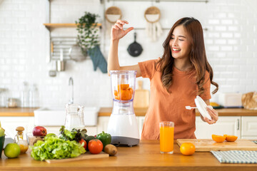 Portrait of beauty healthy asian woman making orange fruit smoothie with blender.young girl preparing cooking detox cleanse and with fresh orange juice in kitchen at home.Diet concept.healthy drink
