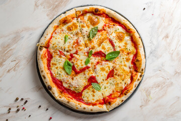 Italian pizza Margherita with cheese and tomato sauce and basil on marble table top view
