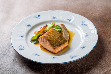 Salmon steak on the grill on plate on brown table