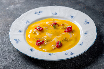 ceviche from dorado on a white plate with raspberries on dark table
