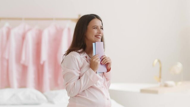 Young pregnant woman holding blue and pink cards, guessing whether it's boy or girl, dreaming at home, free space