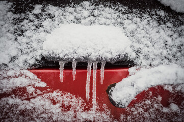 Icicles hang from a car door handle on a snowy afternoon in the winter.  Whistler BC, Canada......