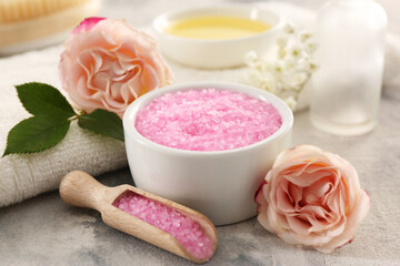 Fototapeta na wymiar Pink sea salt and beautiful flowers on textured table, closeup