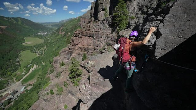 Woman With Backpack on Climbing Route Holding Rocks, Moving Above Green Valley, Slow Motion