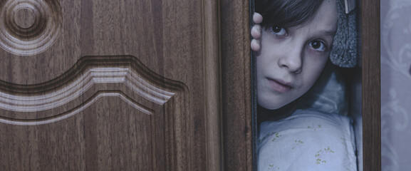 Child scared of nightmare and hiding in closet. Ghost of little girl hid in cupboard at dark night....