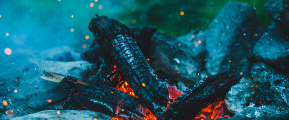 Vivid smoldered firewoods burned in fire closeup. Atmospheric background with orange flame of...