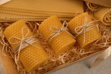 Beautiful yellow beeswax candles and sheets in box, above view - obrazy, fototapety, plakaty