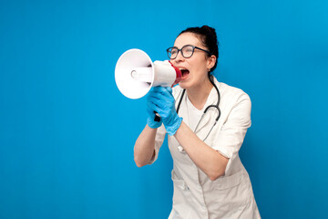 doctor girl in uniform shouting into loudspeaker on blue background, female nurse in medical gown announces