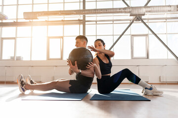 athletic couple in sportswear at crossfit training with ball in the room, woman and man together at...
