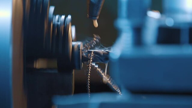 Drilling detail on a lathe with metal shavings. Close-up of a metallic workpiece clamped in a rotating machine chuck. Steel drill bit and twisted swarfes on a green background