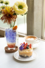 A Banoffee Pie is served in a plastic cup, adorned with flowers and strawberries as decoration.