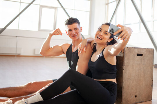 athletic couple in sportswear in training take selfie on smartphone in fitness room, woman and man take pictures