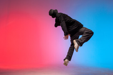 young guy falls upside down in the air, man levitates and flies down in neon lighting, acrobat...