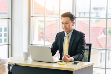 Asian Businessman using laptop at office desk. Man hands typing computer keyboard reading financial graph chart Planning analyzing marketing data. happy Asian business men people working office firm