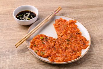 Kimchi pancake (Kimchi jeon or kimchi buchimgae) on plate eating with soy dipping sauce, Korean food