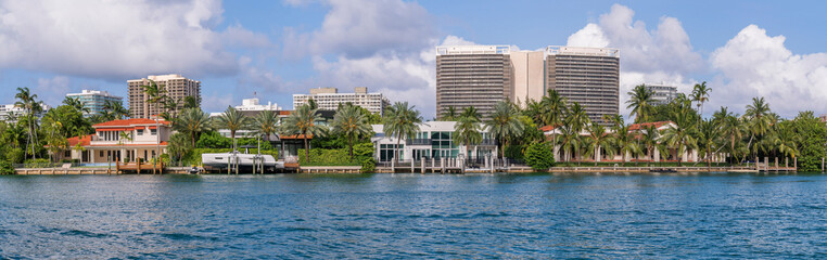 Obraz na płótnie Canvas Miami Beach, Florida- Villas and modern buildings in intracoastal waterway at Biscayne Bay. Panorama of blue waterway at the front near the villas and modern buildings against the cloudy sky.