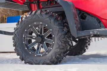 Close-up of wheels of an ATV used by lifeguard on a beach at Destin, Florida. Wheels at the back of a red quad bike on a white sand.