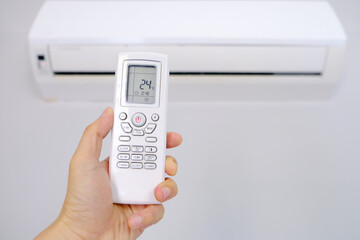 Man's hand using remote control open The air conditioner is cooled to 25 degrees Celsius in his bedroom. Health concepts and energy savings
