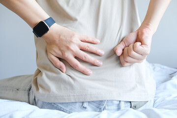 man's hand he is caught at the waist and her back is painful at the back in the room. health concept