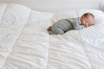 Cute caucasian several days old newborn sleeping on white blanket at home.Adorable,calm, innocent baby indoors.Copy space. Full body shot.Minimalism,lifestyle. 