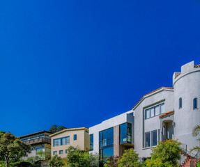 Fototapeta na wymiar San Francisco California homes exterior view with beautiful architecture. Facade of multi-storey houses with lush trees and clear blue sky scenery on a sunny day.