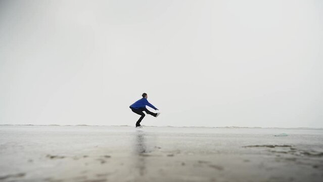 Caucasian woman in a blue sweater is skating on a frozen lake. The figure skater performs the program.