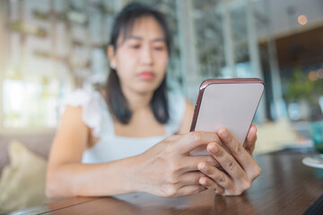 Close-up, woman in white dress sitting with smartphone in restaurant on holiday happily. concept about of technology, social media, online shopping.
