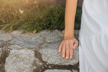 Close-up view, woman wearing white dress sitting on rock wall in resort educating, relaxing happily. concept about of relax, holiday, resort, comfort.